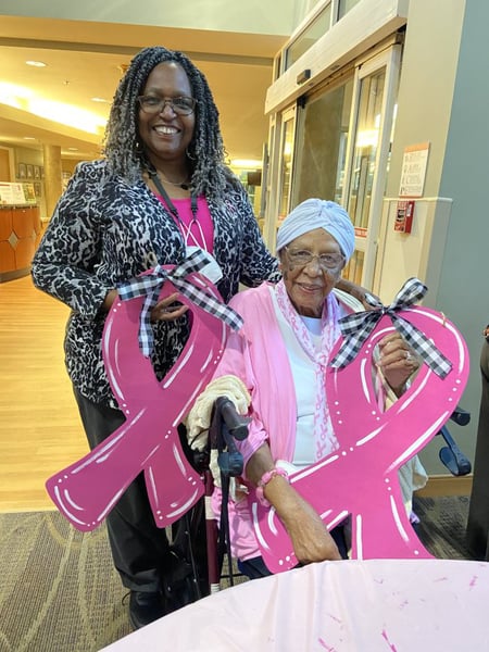 A mother and daughter holding pink ribbons