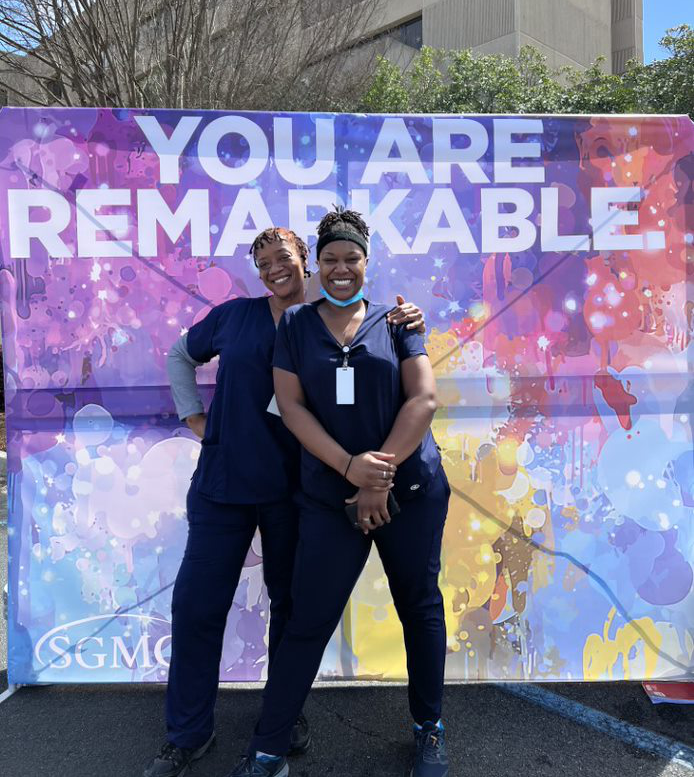 two sgmc foundation employees in front of colorful backdrop
