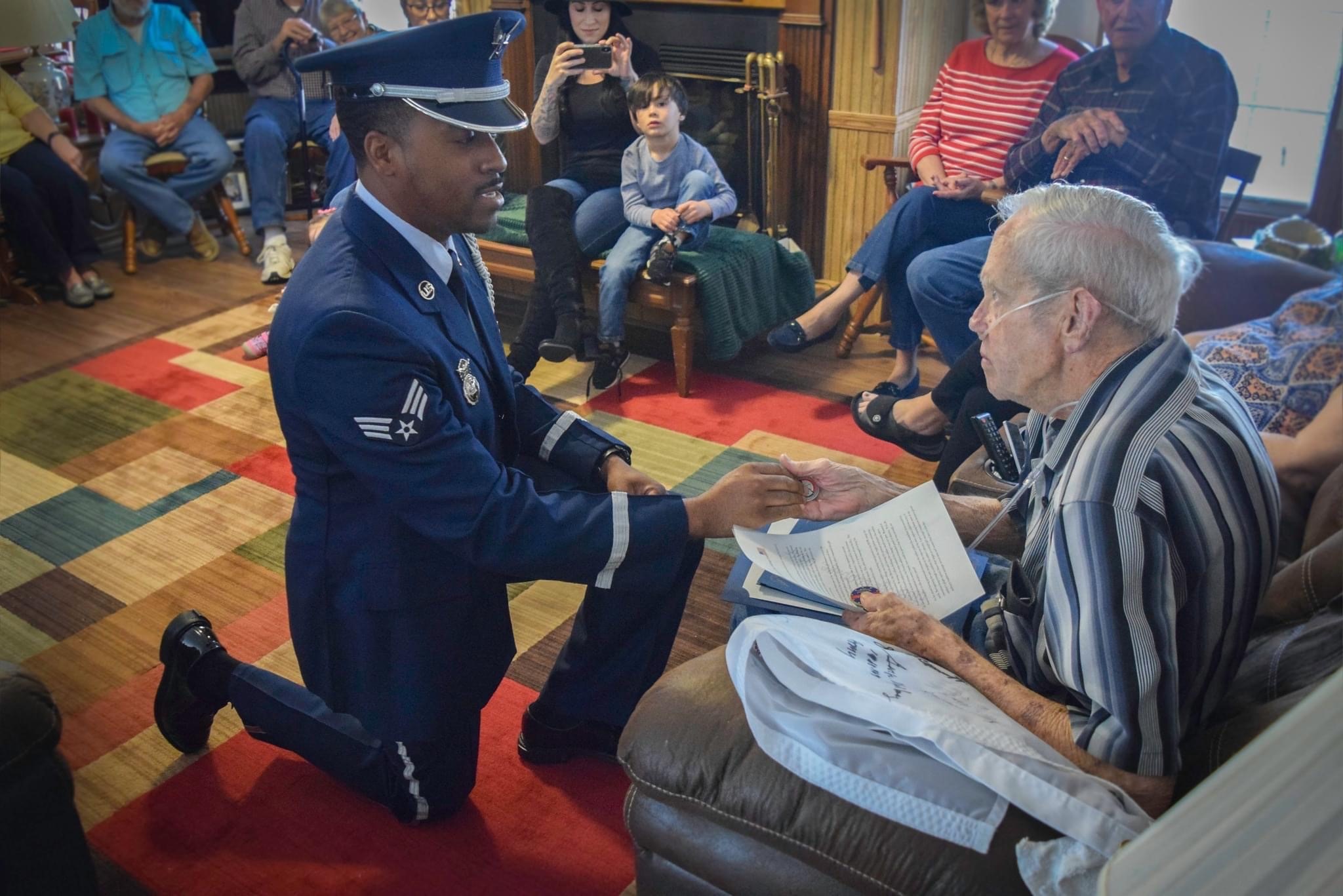 man in military dress kneeling before older man